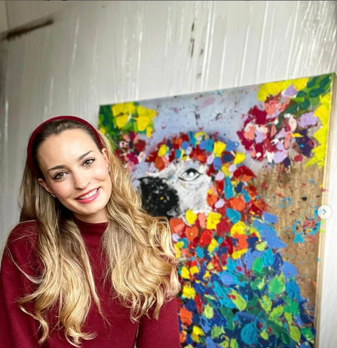 Blonde Frau vor einem Acryl Gemälde eines Papageien