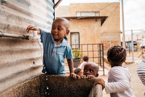 Afrikanische Kinder draußen an einem Wasserhahn