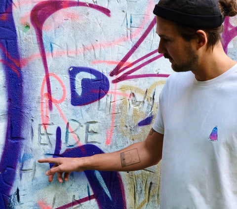 Mann steht vor Graffiti Wand und zeigt auf das Wort Liebe