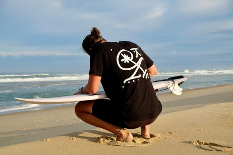 Mann wachst sein Surfboard am Strand