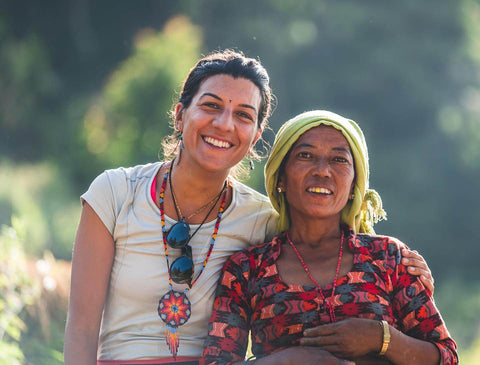 Nepalesische Frau und weiße Frau stehen Arm in Arm und lächeln